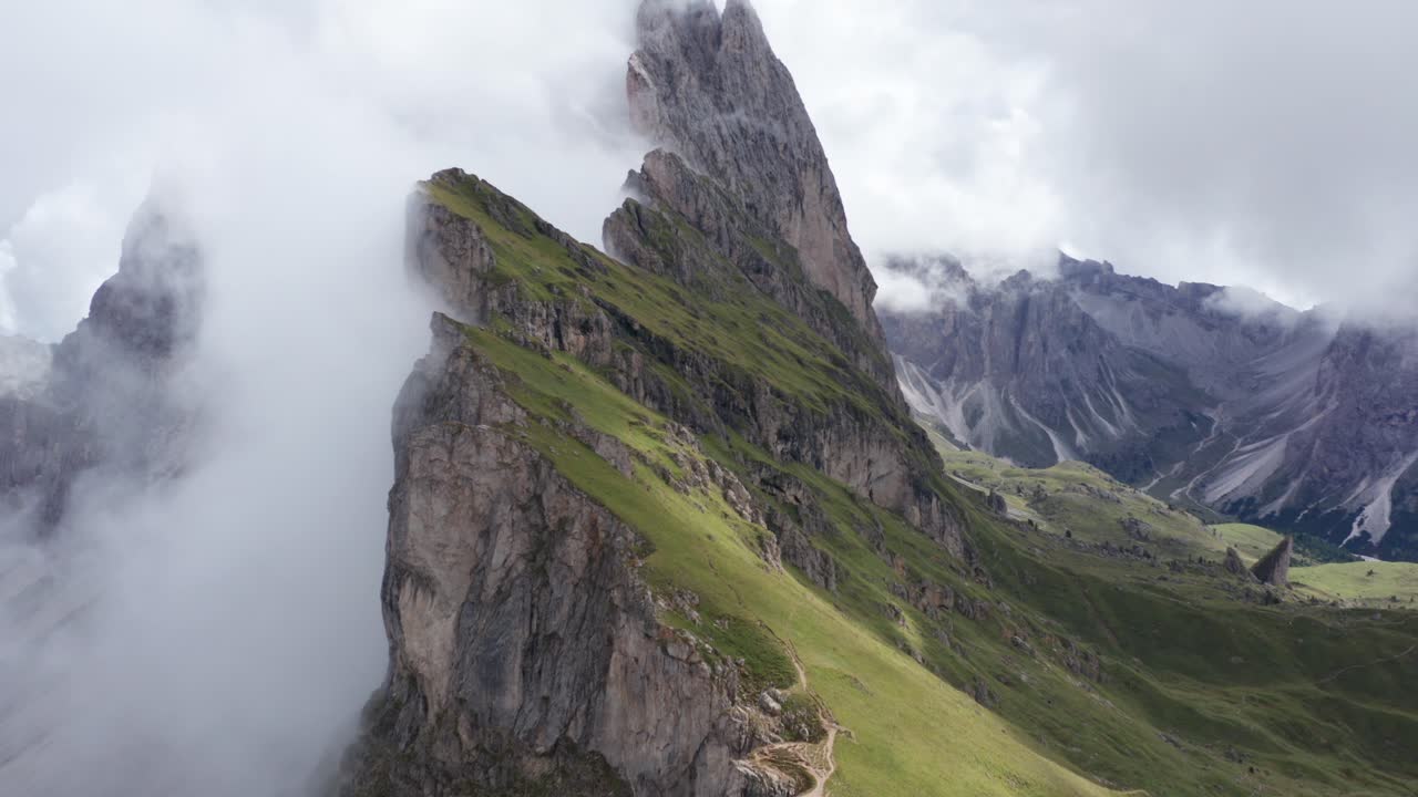 vuelo de drones hacia adelante a lo largo de verdes montañas escénicas cubiertas por densas nubes en el parque nacional puez, dolomitas