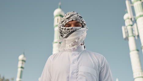 man wearing traditional arab clothing in front of a mosque