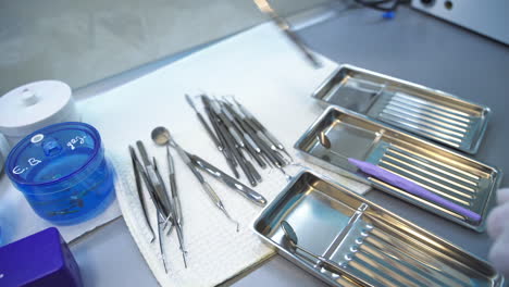 hands in glove put the dental instruments on a little metal trays. medical staff preparing tools for stomatology examination. close up.