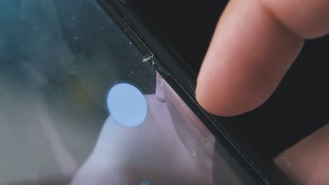 person touches broken phone screen on black background