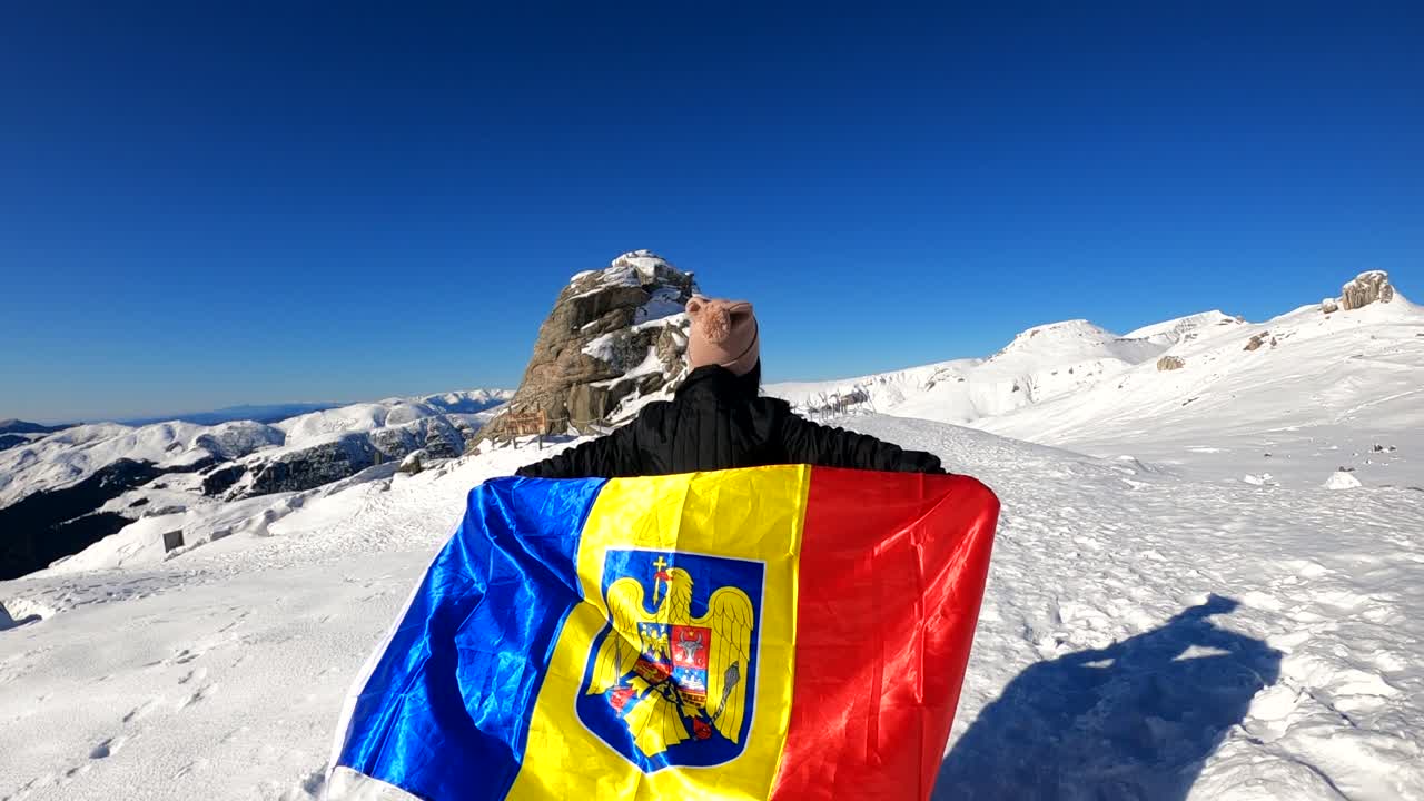 Girl running with the Romanian Flag on top of The Bucegi Mountains, towards the Sphinx rock in Romania - slow motion shot