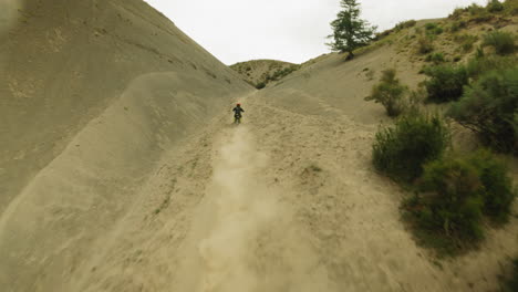 biker rides vehicle along hollow at hilly land fpv. professional motorcyclist on fast machine takes part in motocross racing. challenge for extreme fan