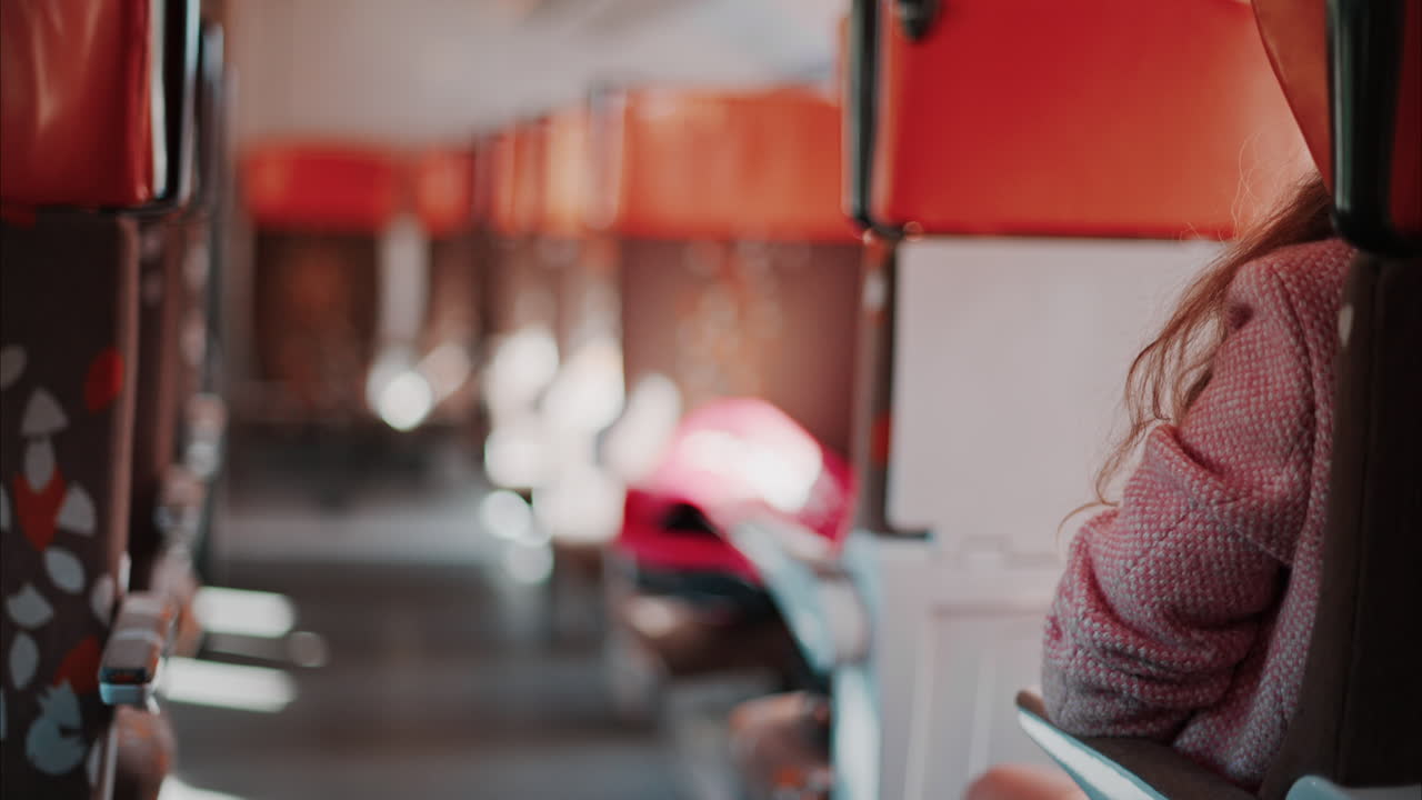 Brunette woman in a pink blazer sitting in the train