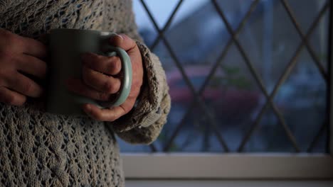 woman holding mug of hot drink in window medium shot