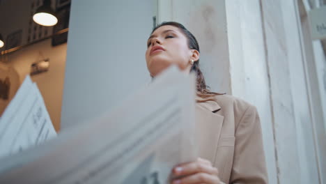 elegant girl reading article in morning press at street closeup. luxurious woman