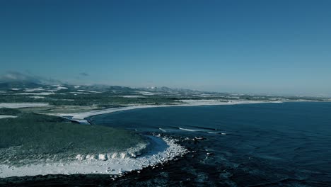 drone shot rising over the coast of hokkaido island in japan in winter