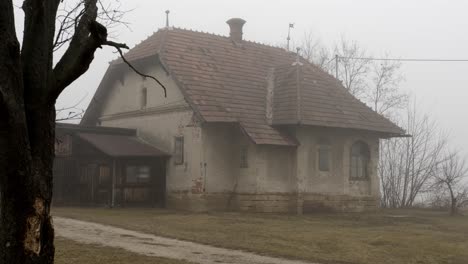 wide shot of mystic old horror house on abandoned farm during cloudy and foggy day