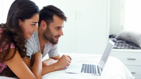 Couple-interacting-with-each-other-while-using-laptop-on-bed