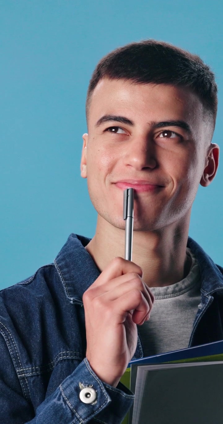 Giovane uomo pensieroso con in mano una penna e un taccuino