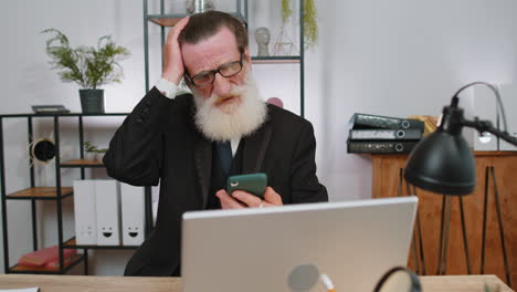 anciano hombre de negocios uso de teléfono inteligente sorprendido por malas noticias, pérdida de fortuna, fracaso, resultados de la lotería