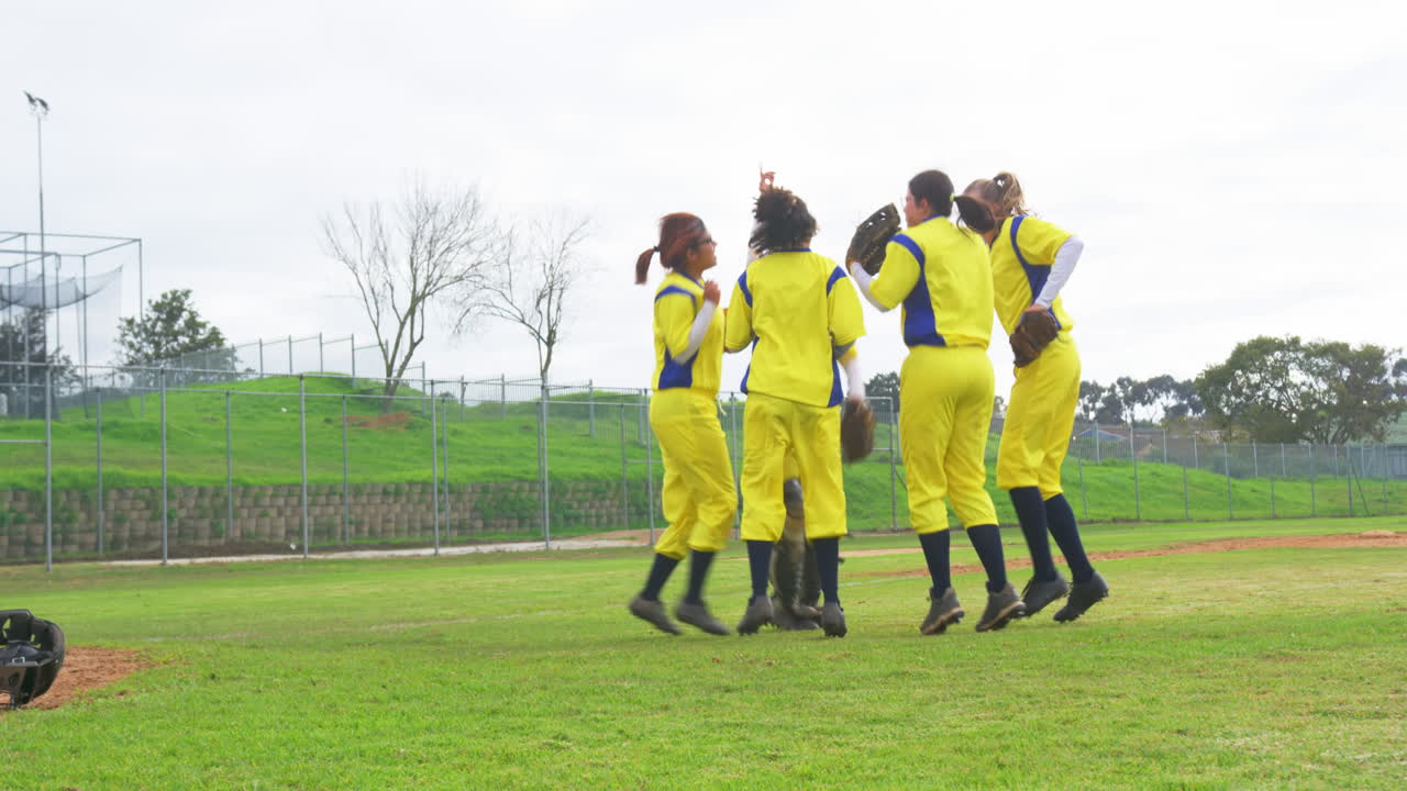 Multiracial female baseball players huddling, celebrating winning the game on a pitch, copy space