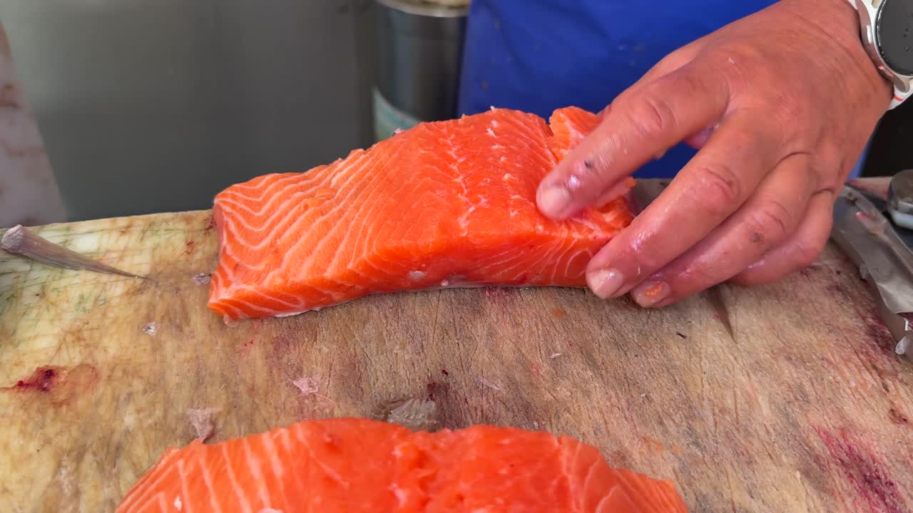 Person cutting and preparing fresh salmon fillet on a wooden board