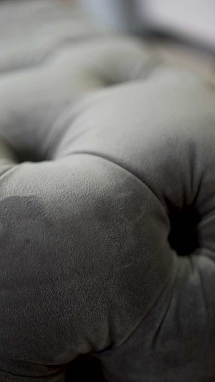 This plush grey cushion features a soft tufted design, highlighting its comfort and style. It adds a touch of elegance to the cozy living room decor