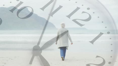 Composite-video-of-ticking-clock-against-rear-view-of-caucasian-senior-woman-walking-on-the-beach