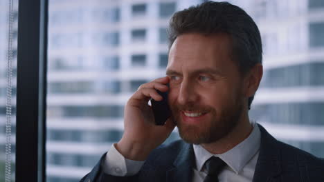 friendly businessman talking phone making corporate call in modern window office