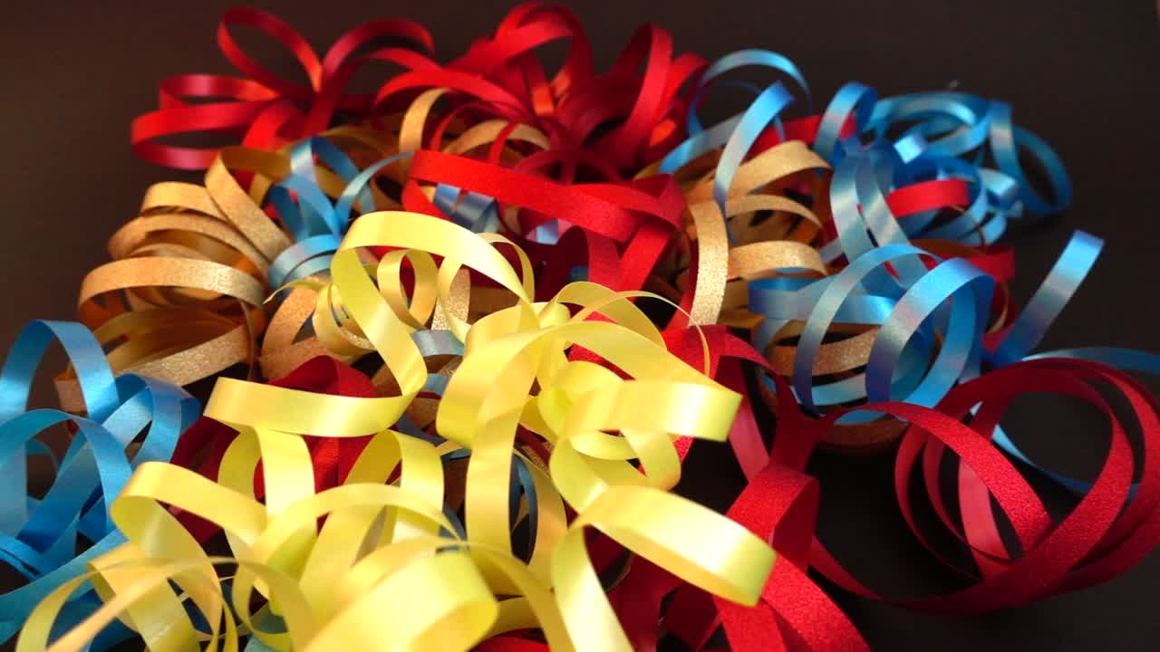 Nastri gialli arricciati che cadono su un mucchio di decorazioni per feste colorate