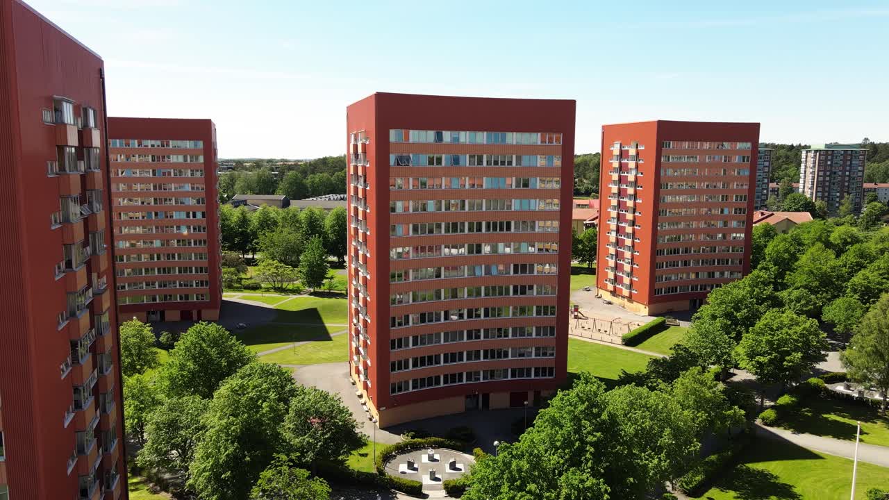 drone volando a través de edificios residenciales contemporáneos contra el cielo azul brillante en västra frölunda, gotemburgo, suecia - tiro elevado