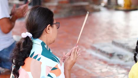 woman praying with incense sticks in ayutthaya, thailand