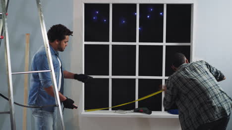 hombre afroamericano mide la longitud de la ventana con un colega