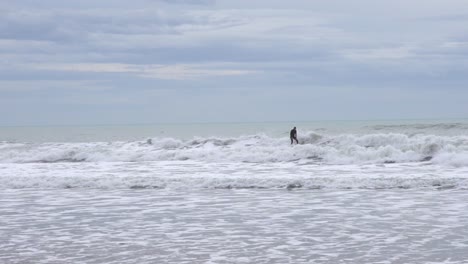 slow motion of a surfer on a stormy day in the mediterranean sea, ride the wave with dirty water and gray day