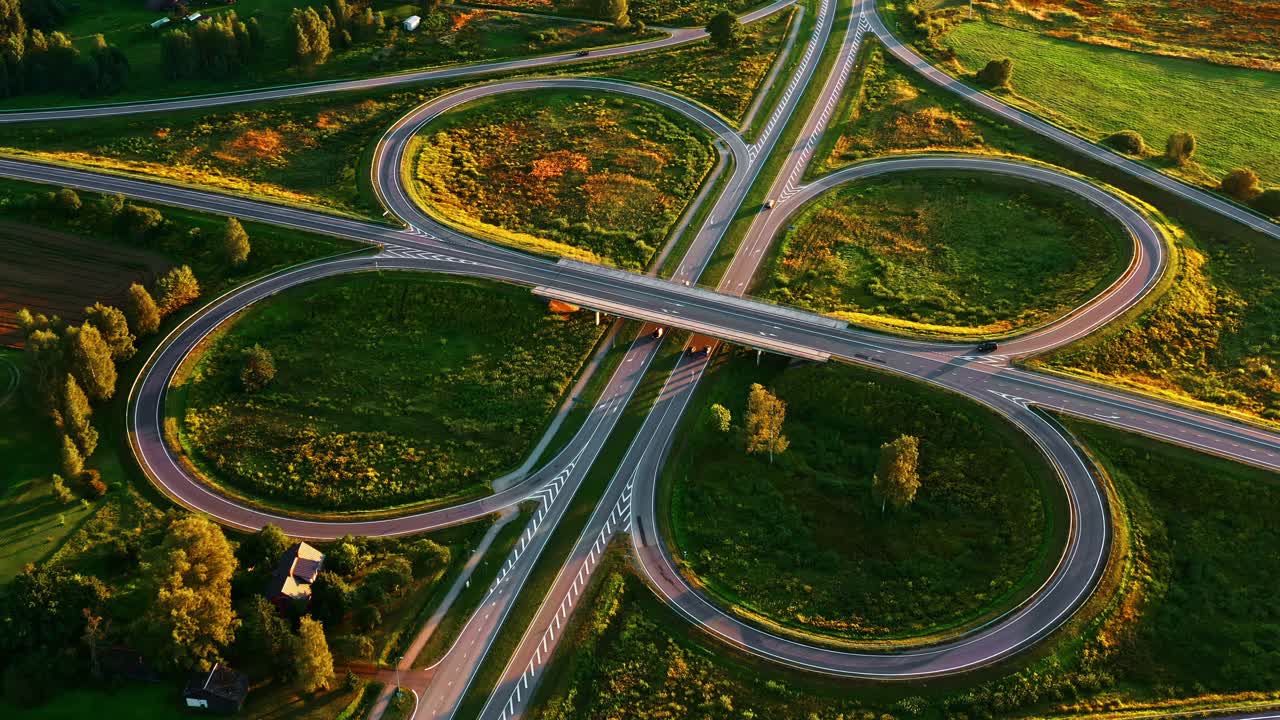 Cloverleaf interchange showing busy highway traffic at golden hour in aerial view