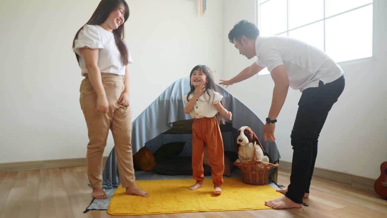 Asian Family Giving High Five To Each Other In Front Of Tent At Home. Family Bonding Concept