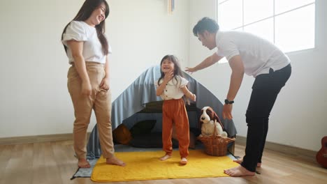 asian family giving high five to each other in front of tent at home. family bonding concept