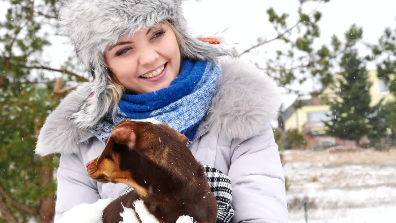 여자 는 겨울 밖 에서 작은 개 와 함께 놀고 있다