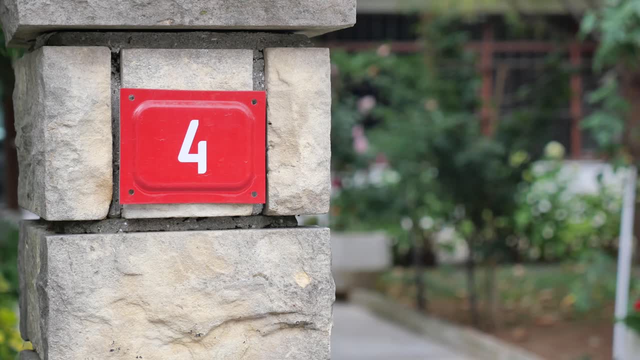 A red sign with the number 4 on a stone pillar