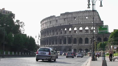 the coliseum in rome with traffic passing