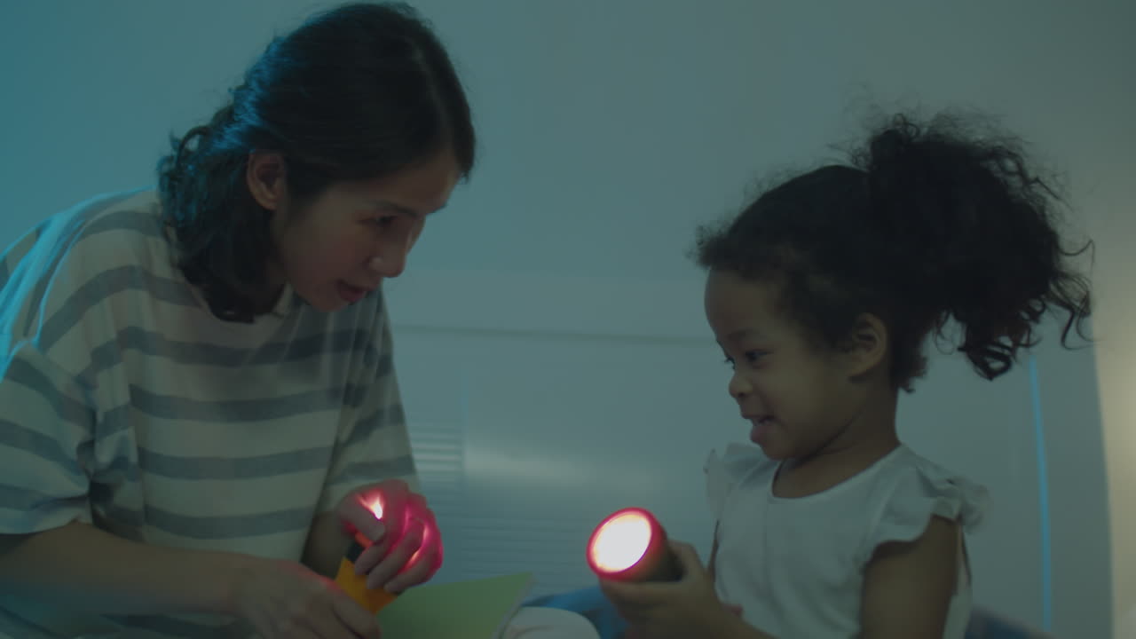 Asian Little Girl and Mother Playing with Flashlights on Bed