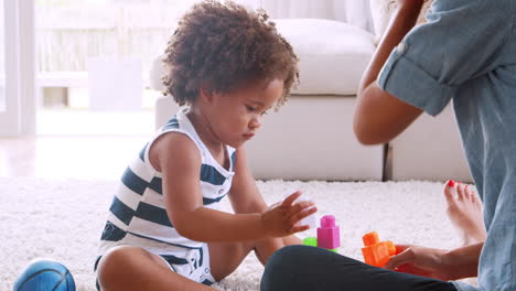 young black girl and her mum playing with plastic bricks