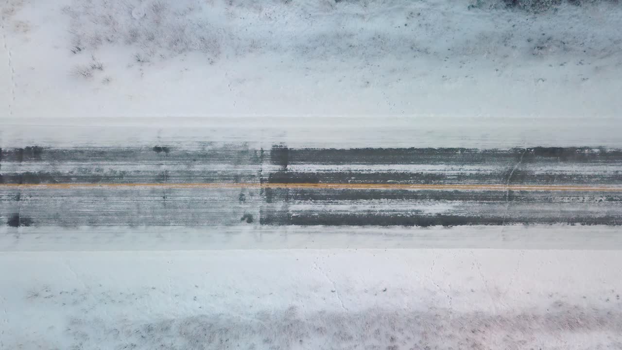 Aerial View of a Car Driving on a Snowy Road in Winter