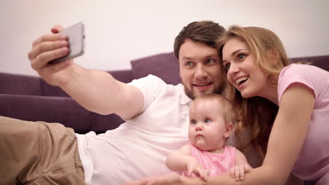 Eltern-Küssen-Baby.-Glückliche-Familie,-Die-Zu-Hause-Ein-Selfie-Foto-Macht