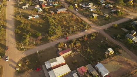 Red-car-driving-on-rural-road-of-small-at-sunset,-Punta-del-Diablo-in-Uruguay