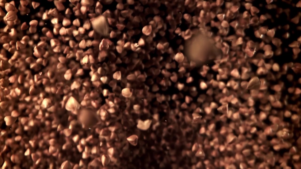 Grani di grano saraceno che cadono in super rallentatore su sfondo nero
