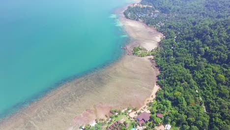 Toma-De-Inclinación-De-Drones-De-La-Costa-Tropical-De-La-Isla-Con-Playa,-Arrecife-De-Coral-Y-Pequeño-Complejo-De-Bungalows