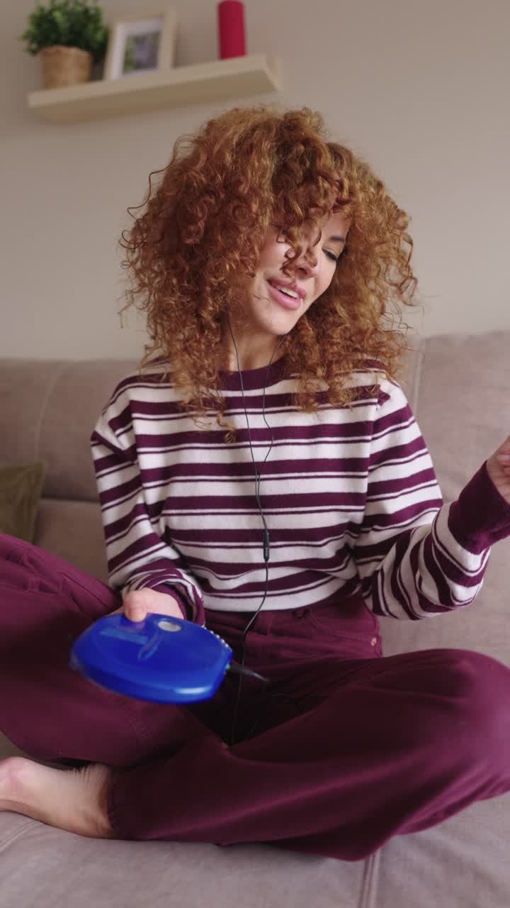 Donna con capelli ricci che ascolta musica su un lettore CD a casa