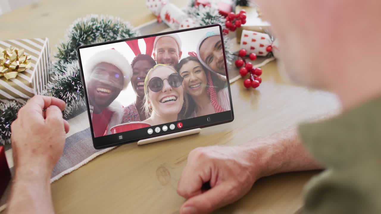 hombre caucásico con decoraciones de navidad teniendo llamada de video de tableta con diversos amigos