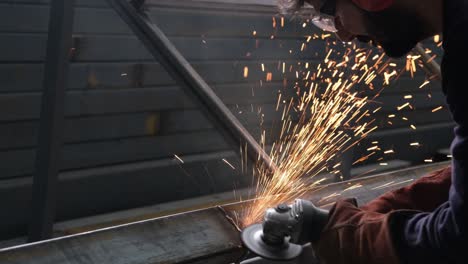 grinding machine, worker makes sparks with grinder in workshop