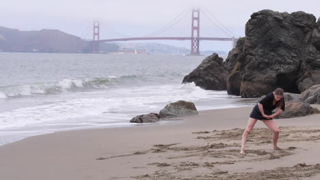 Woman-Interpretive-Dancing-on-Beach-in-Front-of-Golden-Gate-Bridge,-Wide-Shot