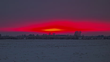 bright red sunset as the sun dips behind the horizon and leaves a glowing crimson sky - time lapse