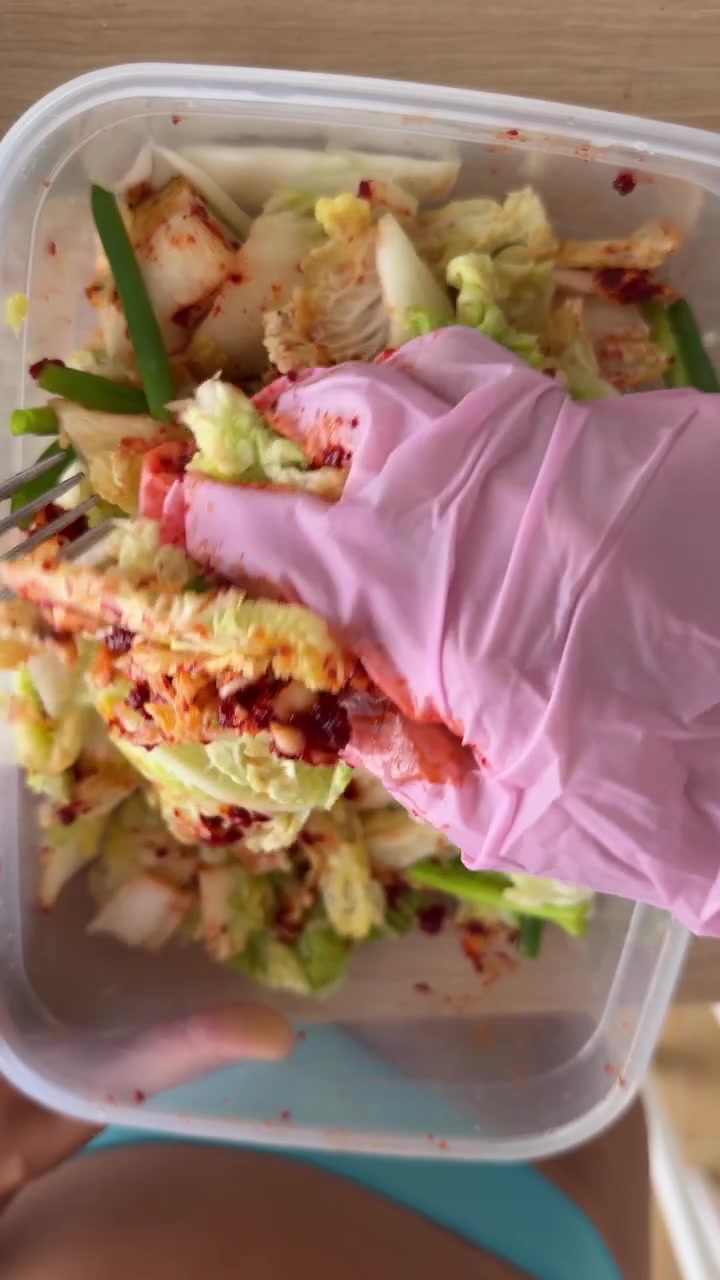 Pessoa misturando kimchi caseiro em um recipiente de plástico