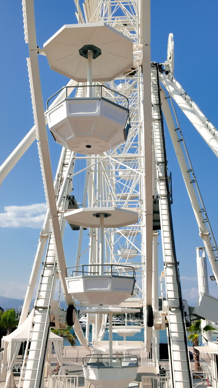 Side view of white ferris wheel rotating in Antibes, France. Vertical