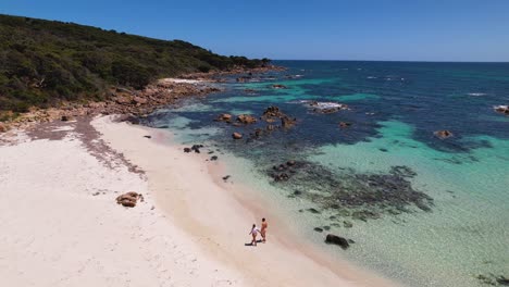 4k-drone-video-of-a-couple-walking-along-the-white-sand-beach-next-to-beautiful-calm-and-crystal-clear-ocean-in-Dunsborough-in-Western-Australia