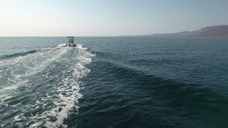 Follow-Drone-Footage-behind-speedboat-cruising-along-ocean-at-Cabo-San-Lucas,-Mexico