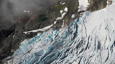 drone dolley shot over the beautiful frozen glacier hardangerjøkulen in norway as thin white clouds roll over the rocks in hardangervidda