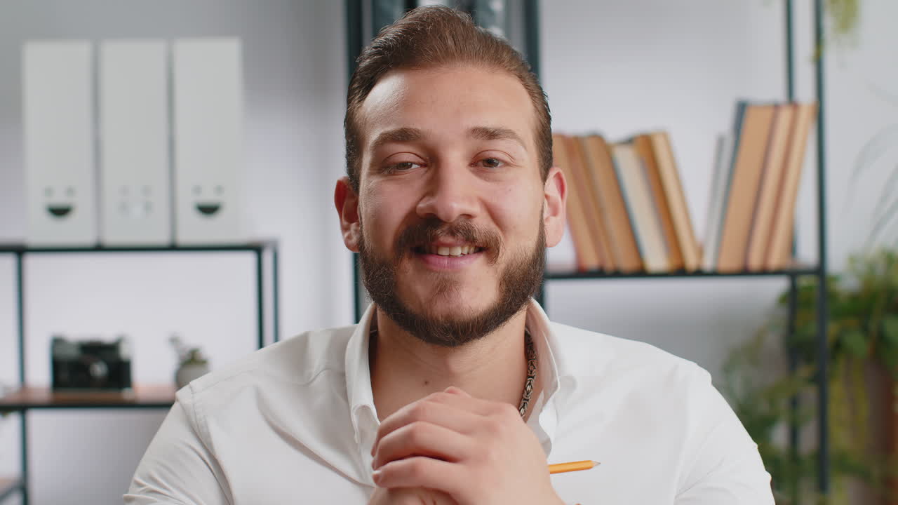 Ritratto di un uomo d'affari felice e sorridente del Medio Oriente in ufficio a casa. Guarda lontano, gira la testa verso la telecamera.