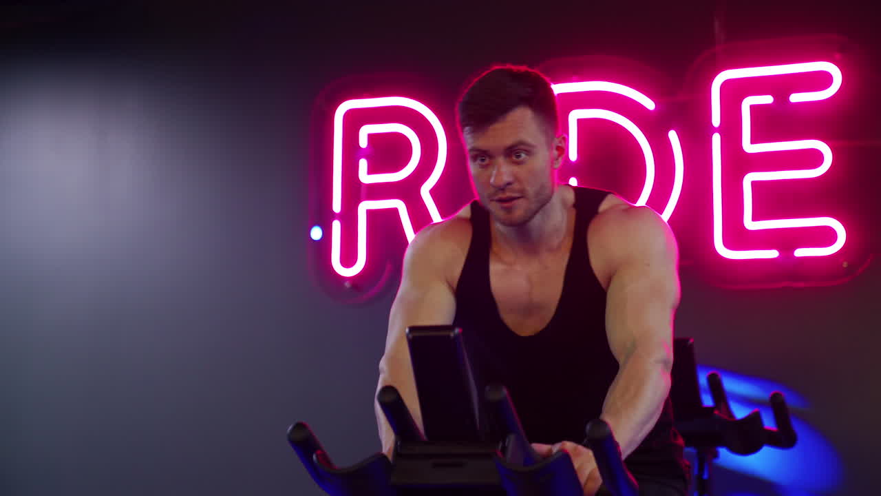 Sportman riding bike at the gym. Man performs aerobic endurance training on the simulators in the gym