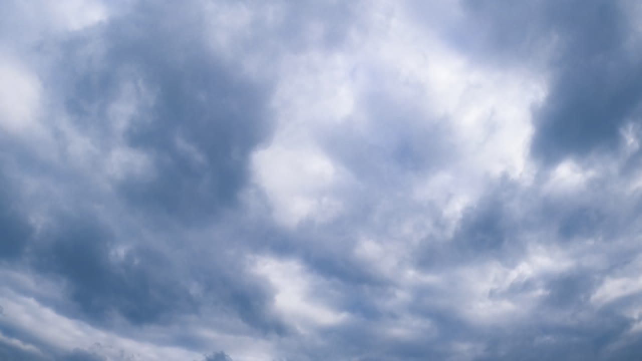 Heavy clouds floating in the atmosphere. Cumulus cloudscape gathering in the sky forming rain. Low angle view. Timelapse.